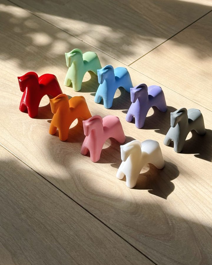 A row of colorful charm figurines showing the NOLA color range