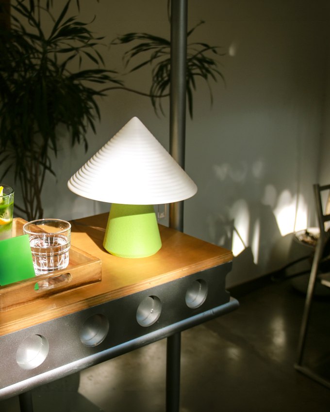 NOLA lamp glowing beside drinks on a lounge table at night