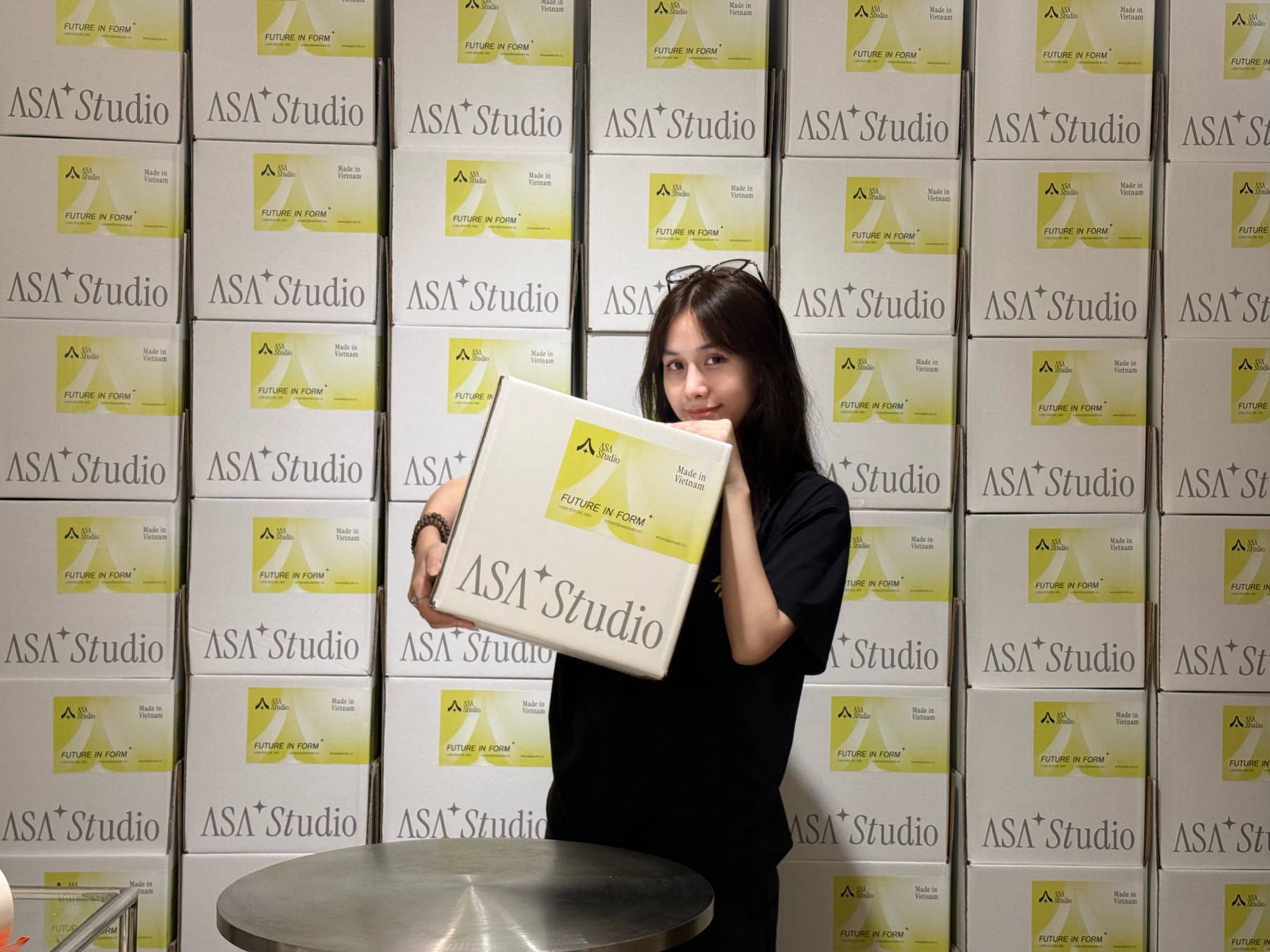 An Asa Studio team member holding a packed NOLA order in front of stacked shipping boxes